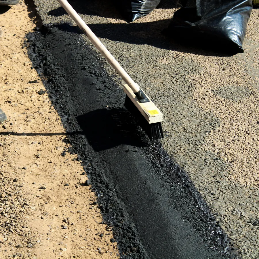 A Virginia Asphalt Services Inc. crew member working an asphalt edge by hand